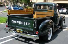 an old green chevrolet pickup truck parked in a parking lot