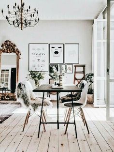 a dining room table with chairs and pictures on the wall above it, along with a chandelier