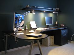 a computer desk with a monitor, keyboard and mouse sitting on top of it next to a lamp