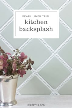 a metal bucket filled with pink flowers on top of a white counter next to a tiled wall