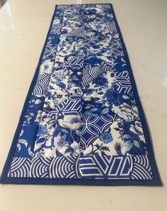 a blue and white table runner with floral designs on the border, sitting on a counter top