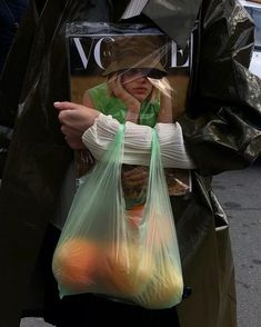 a woman carrying two bags full of oranges