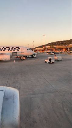 an air plane parked on the tarmac with other planes in the background at sunset