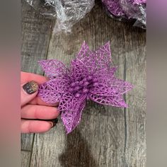 someone is holding a purple crochet star ornament on a wooden table