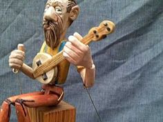 a statue of a man with a guitar sitting on top of a wooden block holding a string