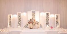 two people sitting on a white chair in front of a stage with candles and flowers