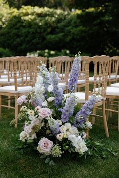 an arrangement of flowers sits on the ground in front of rows of chairs at a wedding ceremony