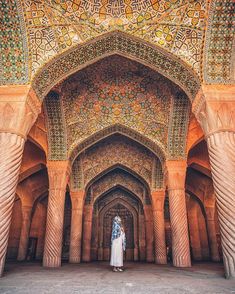 a bride and groom standing in the middle of an ornate archway with intricate tiles on it