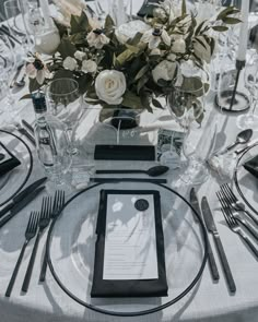 the table is set with black and white place settings, silverware, and floral centerpieces