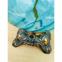 a blue glass vase sitting on top of a wooden table next to a metal stand