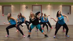 a group of women in blue shirts and black pants are dancing on a wooden floor