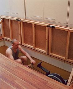 a man kneeling on the floor in front of cabinets