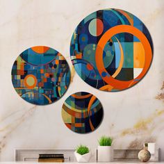 three circular artwork pieces hanging on the wall above a fireplace in a room with marble walls