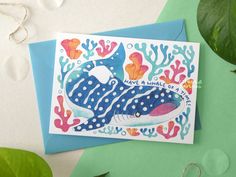 a card with an image of a blue whale on it's back, surrounded by seaweed and corals