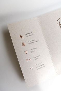 an open wedding program booklet on a white surface with gold foil lettering and monogrammings