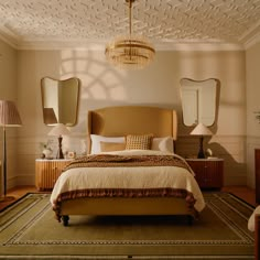 a bedroom with a bed, dressers and mirrors on the wall above it's headboard