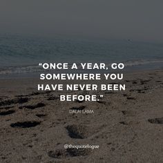 a beach with footprints in the sand and a quote on it that says, once a year, go somewhere you have never been before