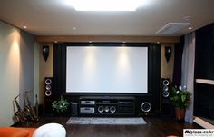 a living room with a large screen and speakers