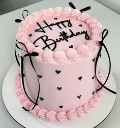 a pink birthday cake with black hearts on it