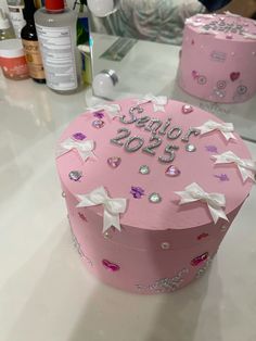 a pink cake decorated with white bows and sequins is sitting on a table