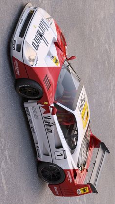 a red and white race car is parked on the pavement with its hood up in front of it