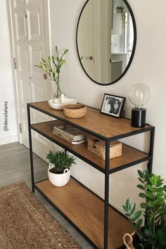 a mirror and some plants on a shelf in a room with a rug underneath it