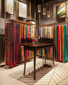 a room filled with lots of different colored fabrics on shelves next to a wooden table