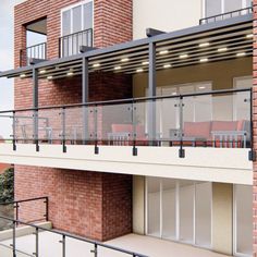 a balcony with chairs and tables on the top floor next to a brick apartment building