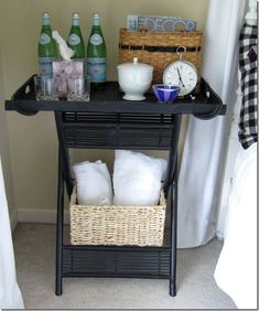 a black table with two baskets and bottles on it next to a clock, towels, and other items