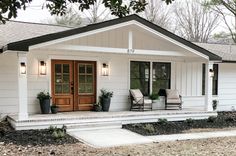 a white house with two chairs on the front porch