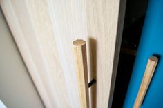 two wooden handles are on the door and one has a blue handle that is attached to it