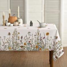 a table topped with a white table cloth covered in lots of flowers and candles next to pumpkins