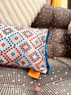 a close up of a pillow on a couch with pillows in the back ground and an orange piece of paper sticking out of it