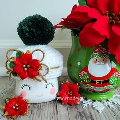 a christmas decoration with poinsettis and a santa clause hat next to a green vase