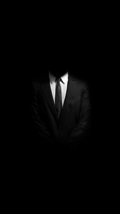 a man wearing a suit and tie in the dark