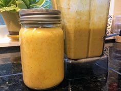 a jar filled with yellow liquid next to a blender