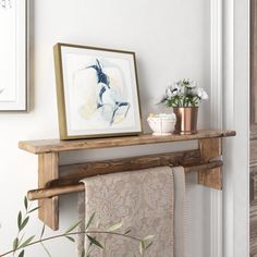 a towel rack with towels hanging on it next to a painting and potted plant