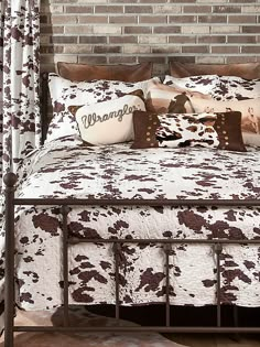 a bed with brown and white pillows on top of it next to a brick wall