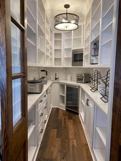 a kitchen with white cabinets and wood floors