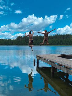 two people jumping into the water from a dock