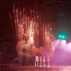 several people standing on stage with fireworks in the background