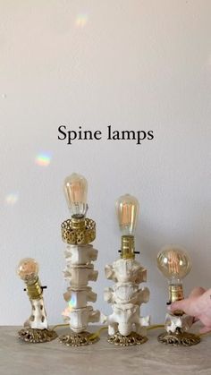 a person is pointing at some light bulbs on a table with the words spine lamps above them