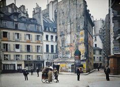 an old photo of people walking and riding bikes in front of buildings with graffiti on the walls