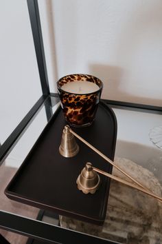 a candle sits on top of a black table with a leopard print glass bowl and silver candlestick