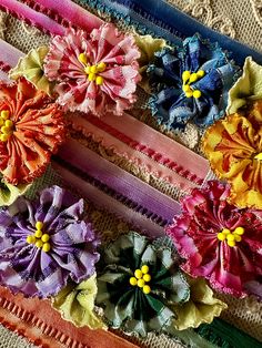 four different colored flowers are on a piece of fabric