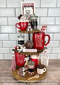 a three tiered tray with coffee mugs and other items on it, along with a sign that says hot cocoa