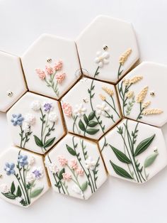 some cookies decorated with flowers and leaves on top of each other in hexagonal shapes