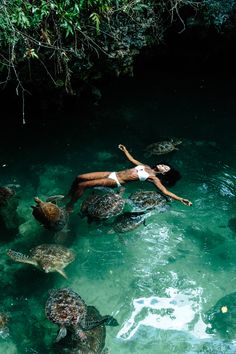 a woman laying on top of turtles in the water