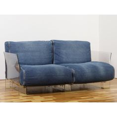 a blue couch sitting on top of a hard wood floor next to a white wall