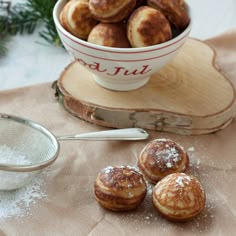 some pastries are in a bowl and on a wooden tray next to a measuring spoon